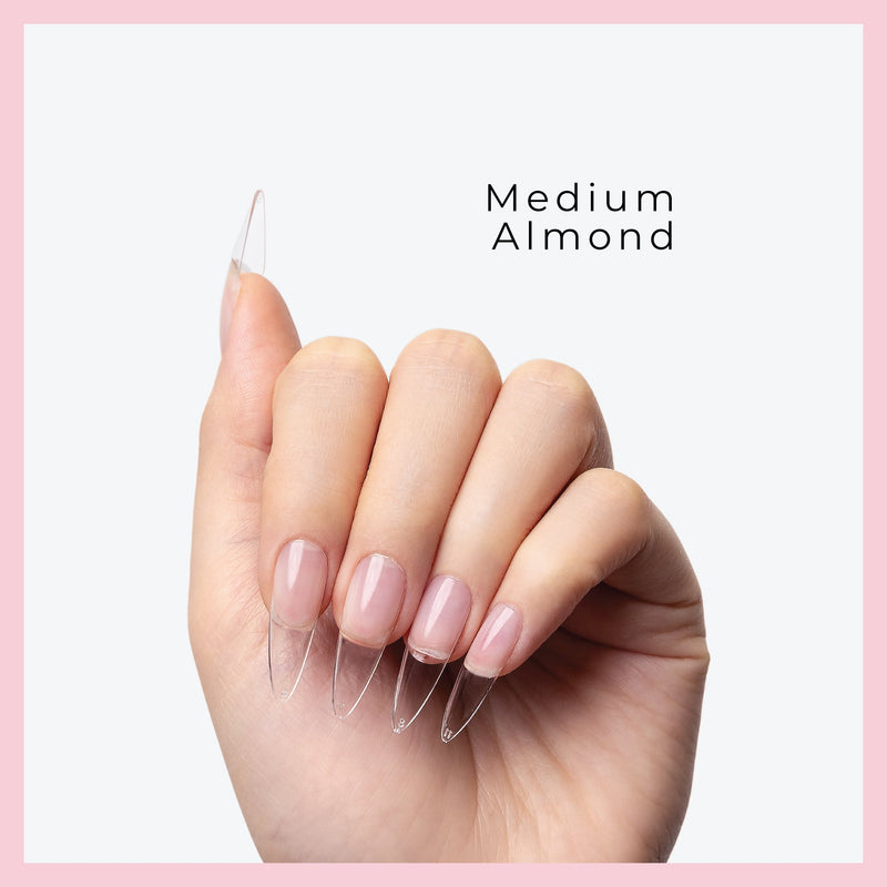 Curacoro medium Almond Soft Gel Nail Tips on a hand, featuring natural nails with clear extensions, set against a light gray background with a pink border.