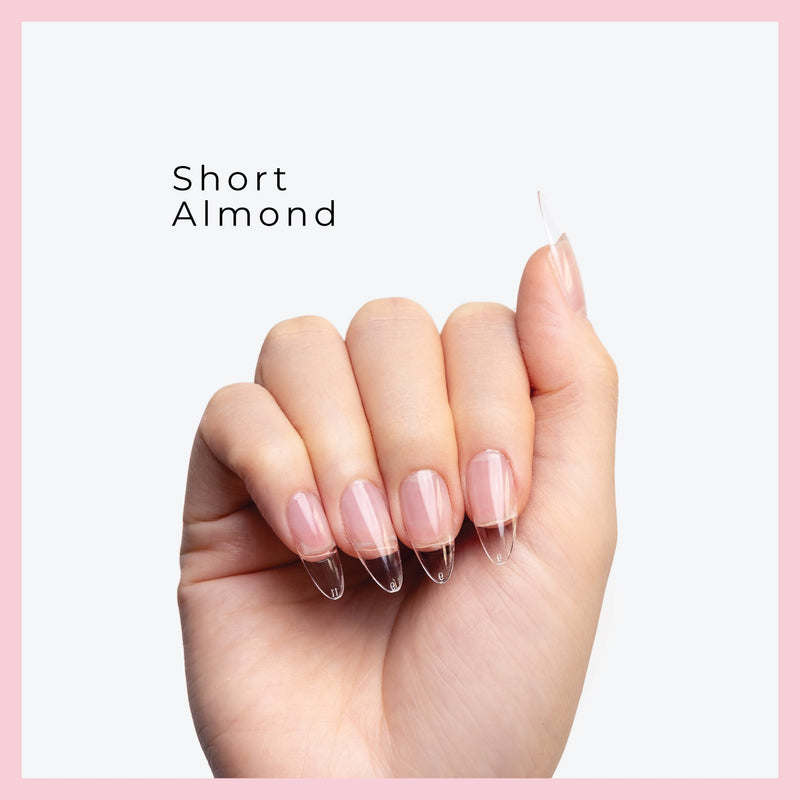 Curacoro short Almond Soft Gel Nail Tips on a hand, featuring natural nails with clear extensions, set against a light gray background with a pink border.