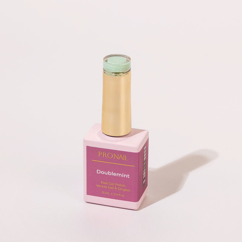 A Doublemint nail polish bottle with a gold cap casting a shadow on a white background.