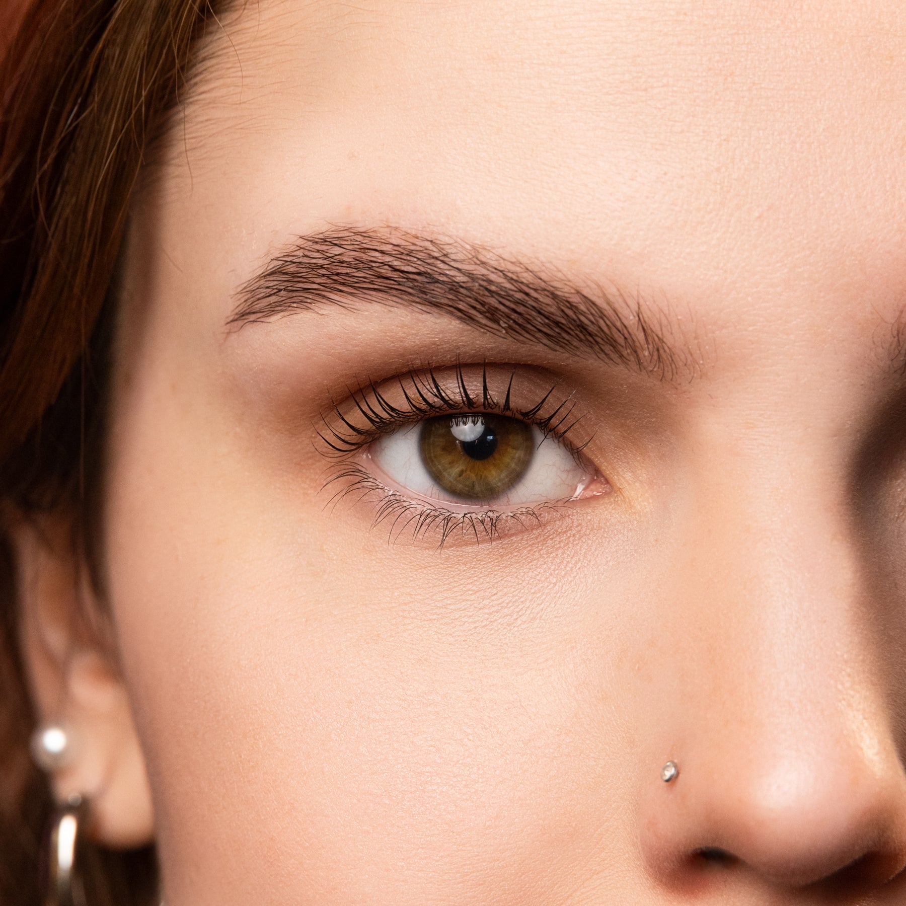 Close-up of an eye with natural lashes after a nourishing serum treatment, showcasing a healthy and glossy appearance.