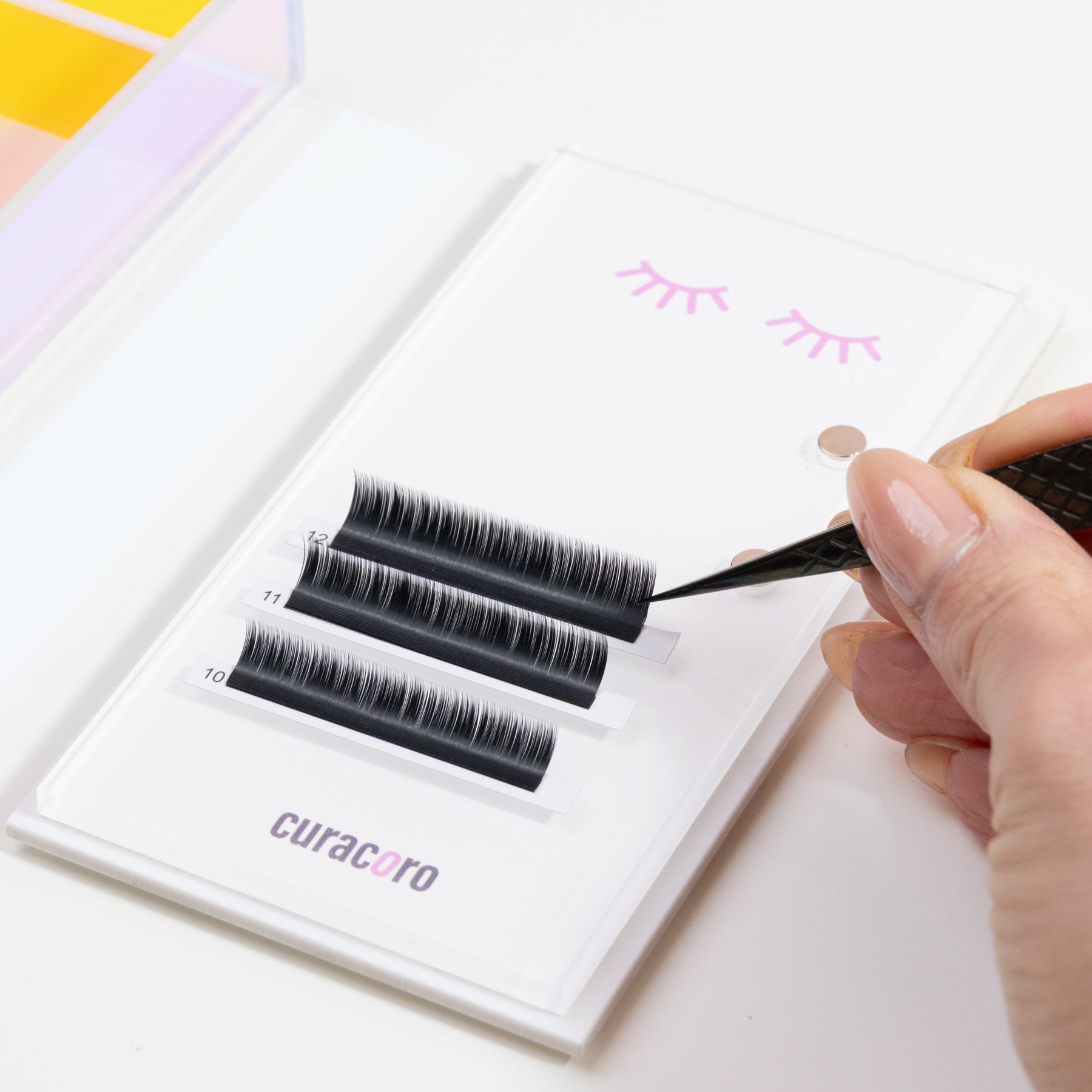 Curacoro magnetic lash tile with labeled lash strips and iridescent tweezer, designed for precise lash application.