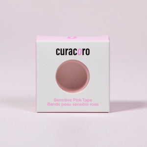 Curacoro sensitive pink tape for eyelash extensions in white and pink packaging, displayed on soft pink background