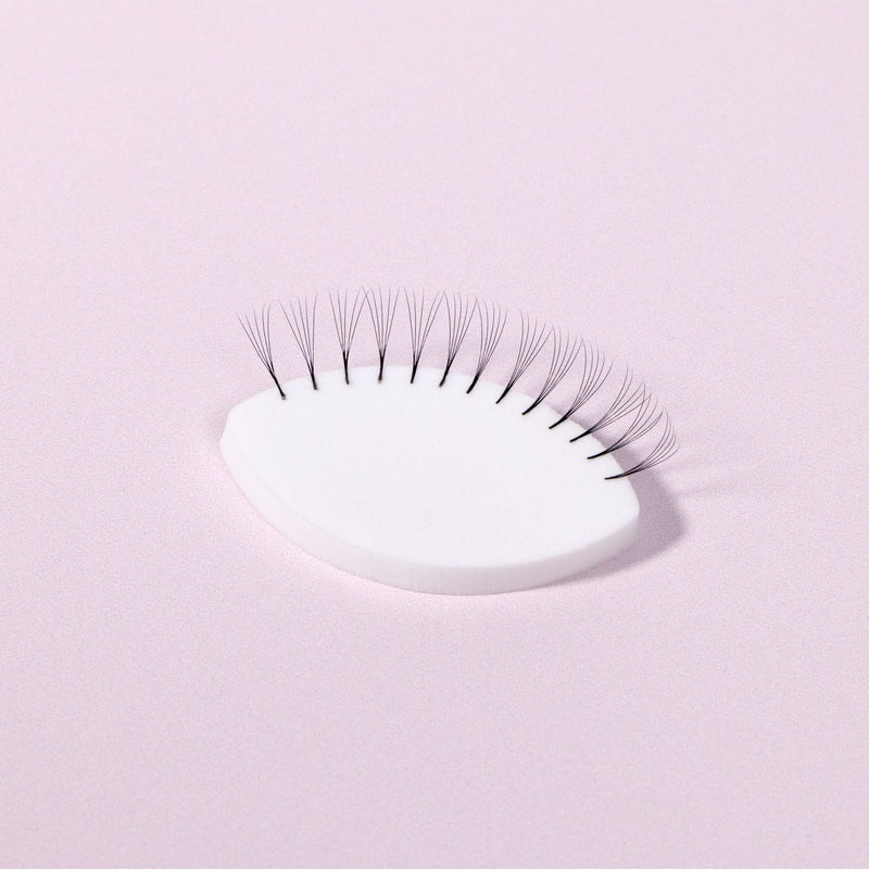 A White Lash Practice Sponge over a light pink background. 