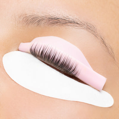 Close-up of Curacoro lash lift rod in pink used on natural lashes, providing a lifted and curled lash effect on a white pad.