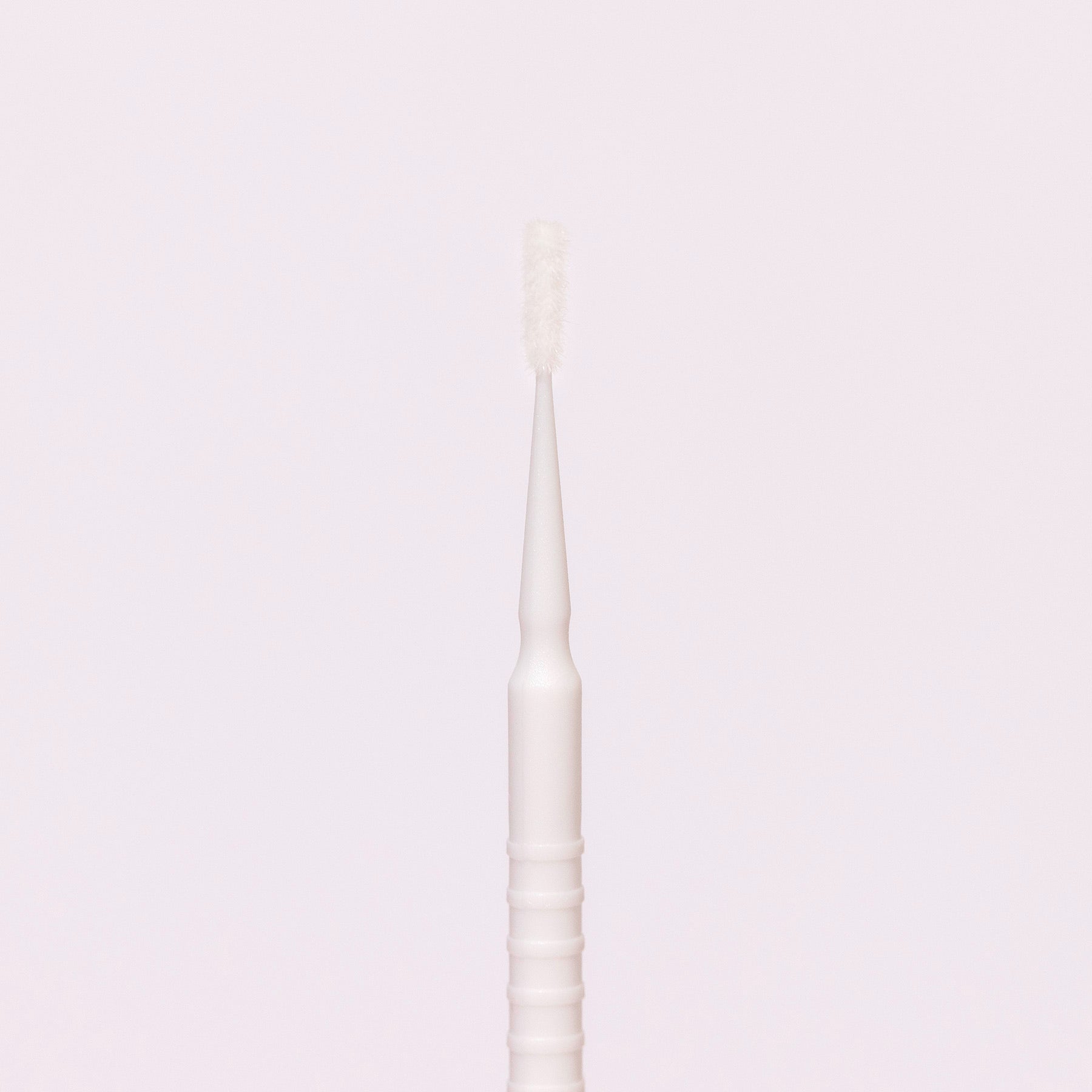 White disposable micro applicator with a fine brush tip, ideal for precise application of beauty products.