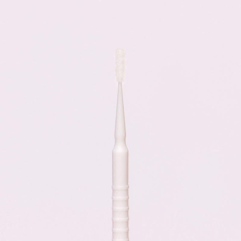 White disposable micro applicator with a fine brush tip, ideal for precise application of beauty products.