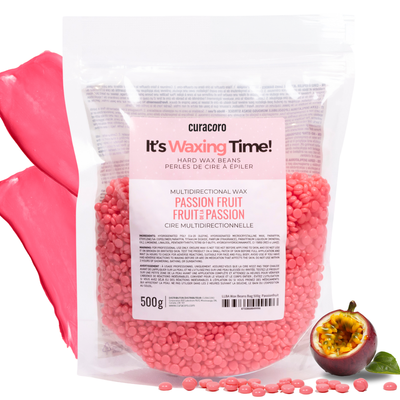 A bag of pink wax beans surrounded by aloe leaves and wax droplets on a white background.