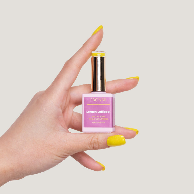 LLBA Lemon Lolipop Gel Polish bottle held in a hand, showcasing a Lemon Lolipop shade on nails with a glittery finish against a light background."