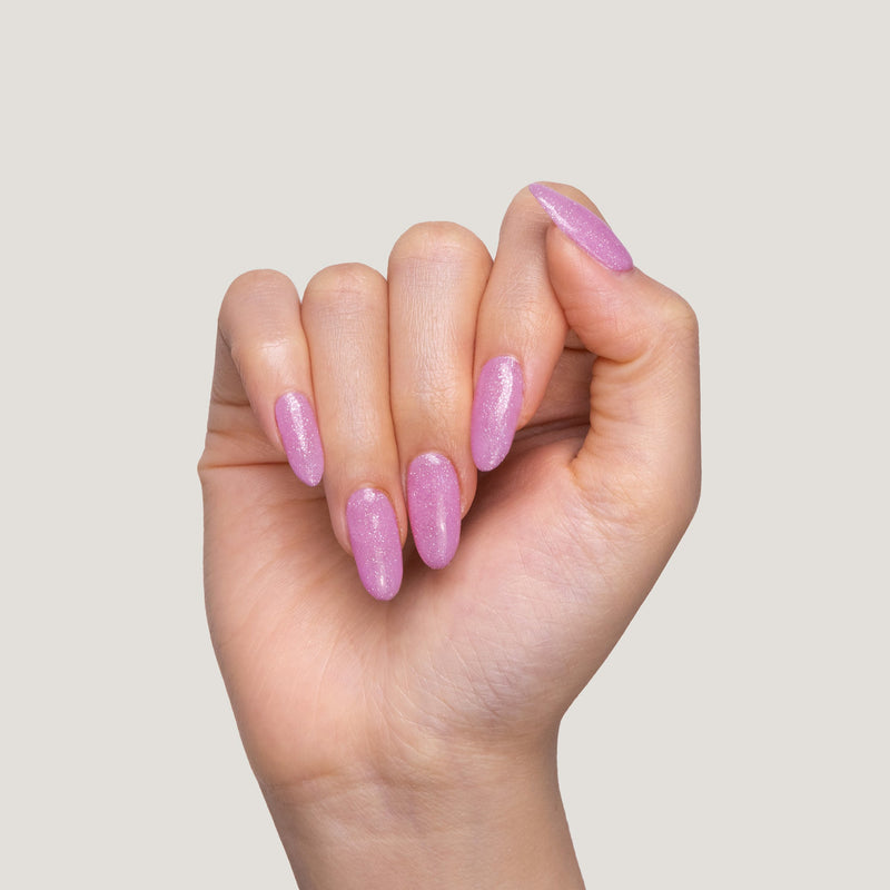 A hand with long, glossy Strawberry Stardust nails held against a light beige background.