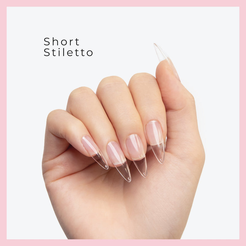 Curacoro Short Sitletto Soft Gel Nail Tips on a hand, featuring natural nails with clear extensions, set against a white background with a pink border.