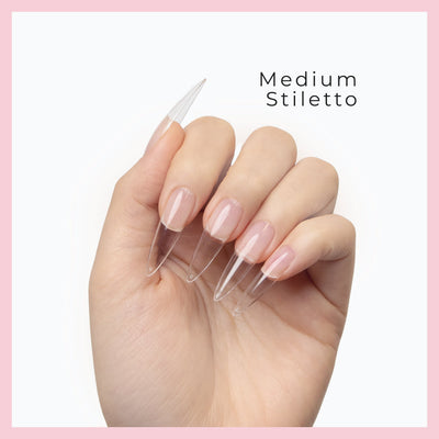 Curacoro Medium Sitletto Soft Gel Nail Tips on a hand, featuring natural nails with clear extensions, set against a white background with a pink border.