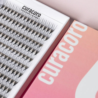 Curacoro lash tray with triple-layered lashes in white and pink packaging on a neutral background.