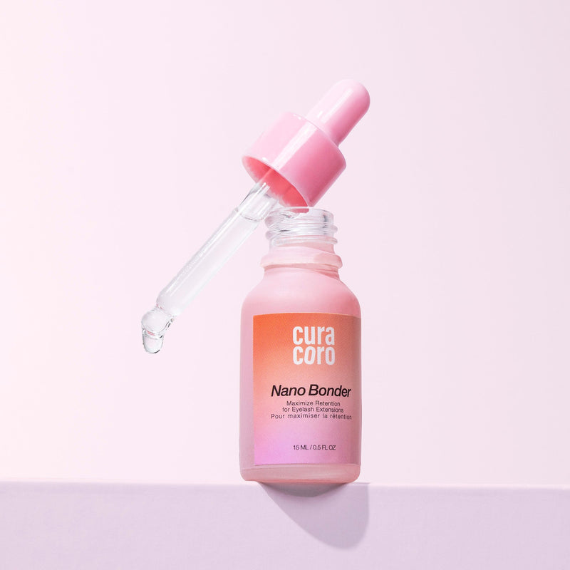 Curacoro Nano Bonder bottle with dropper dispensing liquid, 15 ml, on a pink background.