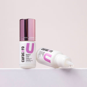 Curacoro Perfect Clear Eyelash Glue, 5mL bottle with purple cap and precision applicator, on neutral background.