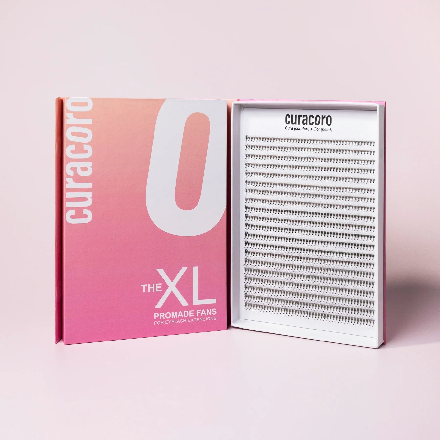 Curacoro XL Promade Fans for eyelash extensions, featuring a sleek pink and white box with an open tray showcasing narrow, slim lash fans arranged neatly.