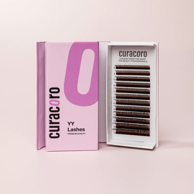 Brown YY Lashes with open case standing in front of a pink background.