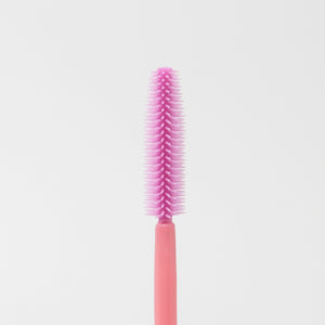 Image of the texture of a disposable pink silicon brush wands for eyelashes and brows.